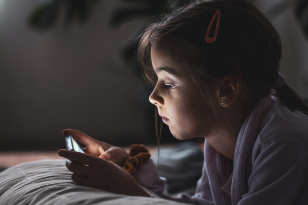 little-girl-uses-smartphone-lying-pillow-home